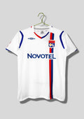 Olympique Lyonnais domicile 2008-2009 : maillot blanc Umbro avec une fine bande verticale bicolore rouge et bleue passant sous le blason, col en V bleu et rouge, sponsor Novotel. GoalKits