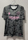 Inter Miami CF x BAPE : Maillot à motif camouflage gris et anthracite avec logos roses et sponsor "A BATHING APE". GoalKits