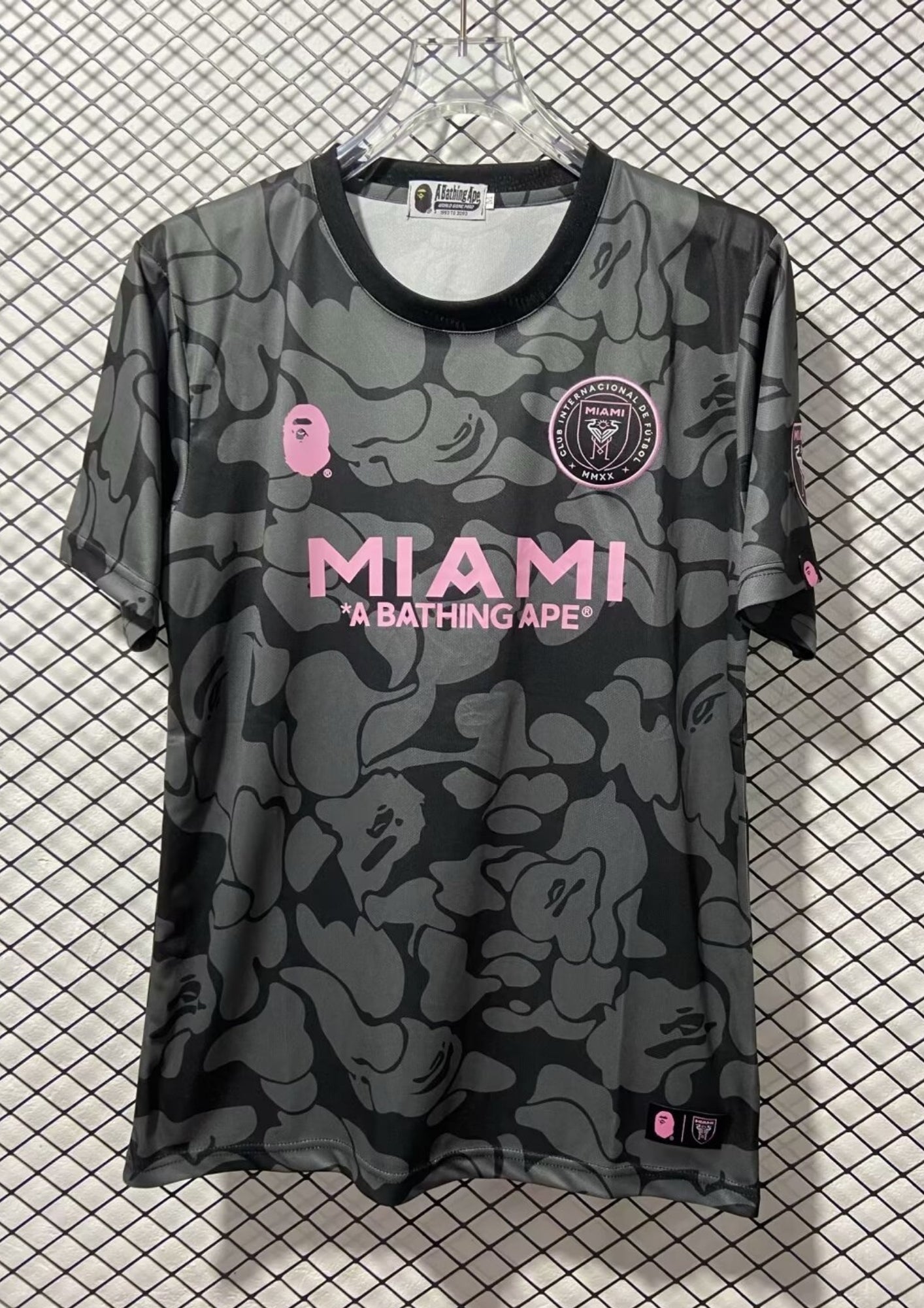 Inter Miami CF x BAPE : Maillot à motif camouflage gris et anthracite avec logos roses et sponsor "A BATHING APE". GoalKits