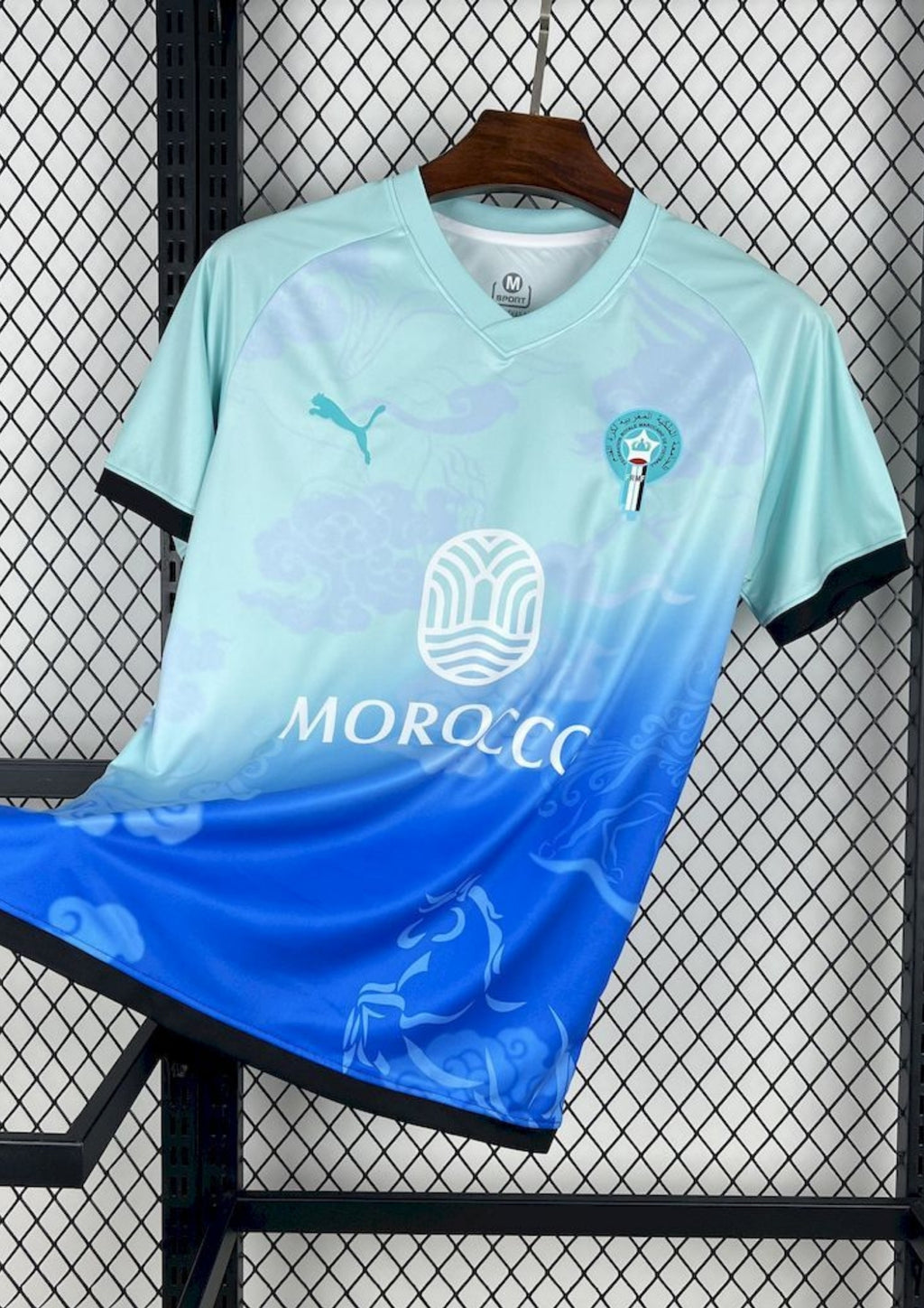 Maroc (Aqua) Dégradé bleu ciel et bleu roi, motifs de nuages et chevaux, logos Puma et FRMF. GoalKits