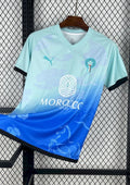 Maroc (Aqua) Dégradé bleu ciel et bleu roi, motifs de nuages et chevaux, logos Puma et FRMF. GoalKits