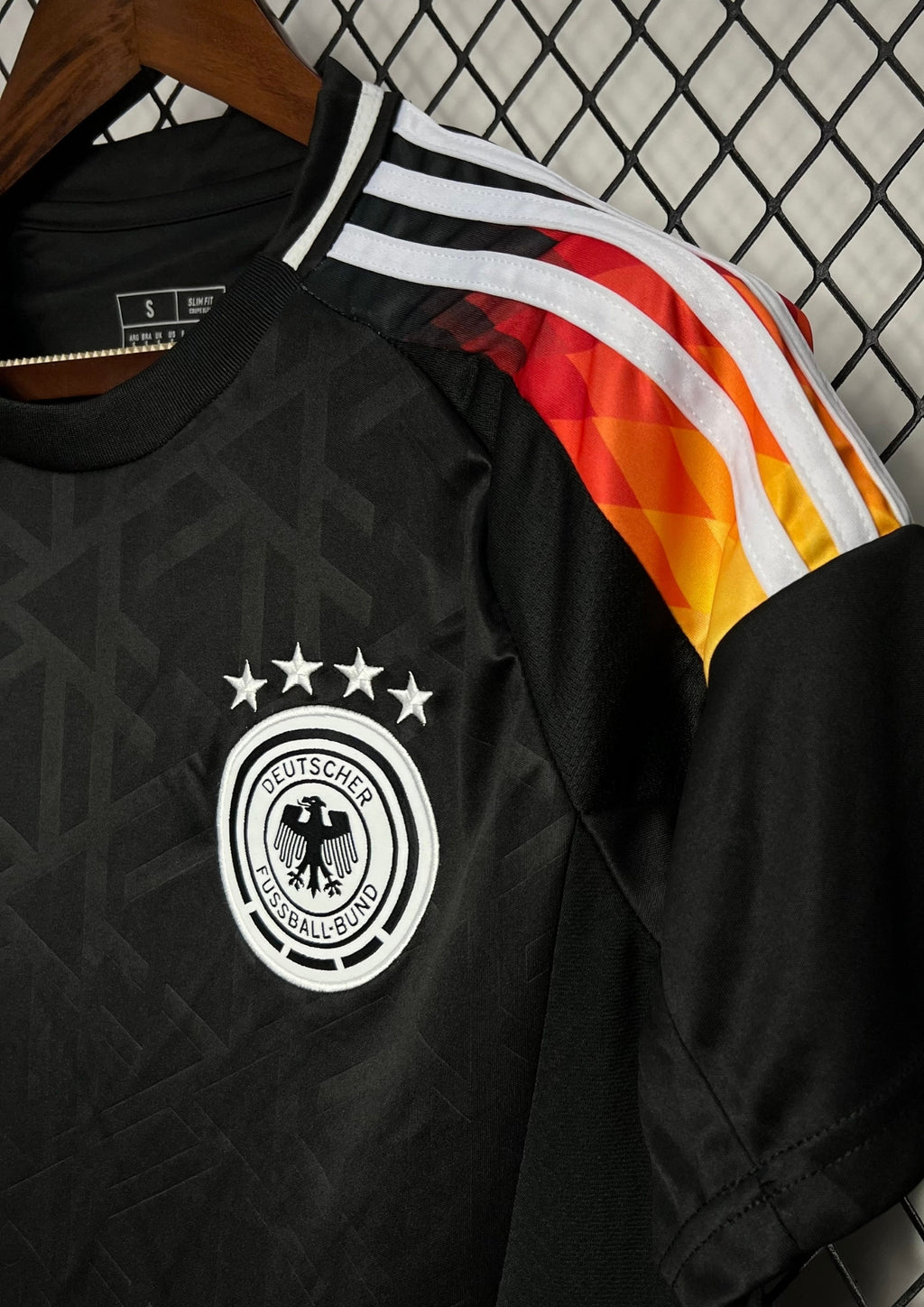 Allemagne (Édition Noir & Feu) Noir avec dégradé tricolore sur les épaules, motifs géométriques ton sur ton, logos Adidas et DFB blancs. GoalKits