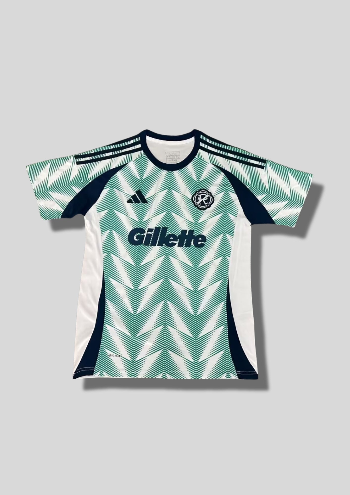 New England Revolution Pre-Match 24/25 : Blanc avec motifs graphiques en chevrons verts et sponsor "Gillette". GoalKits
