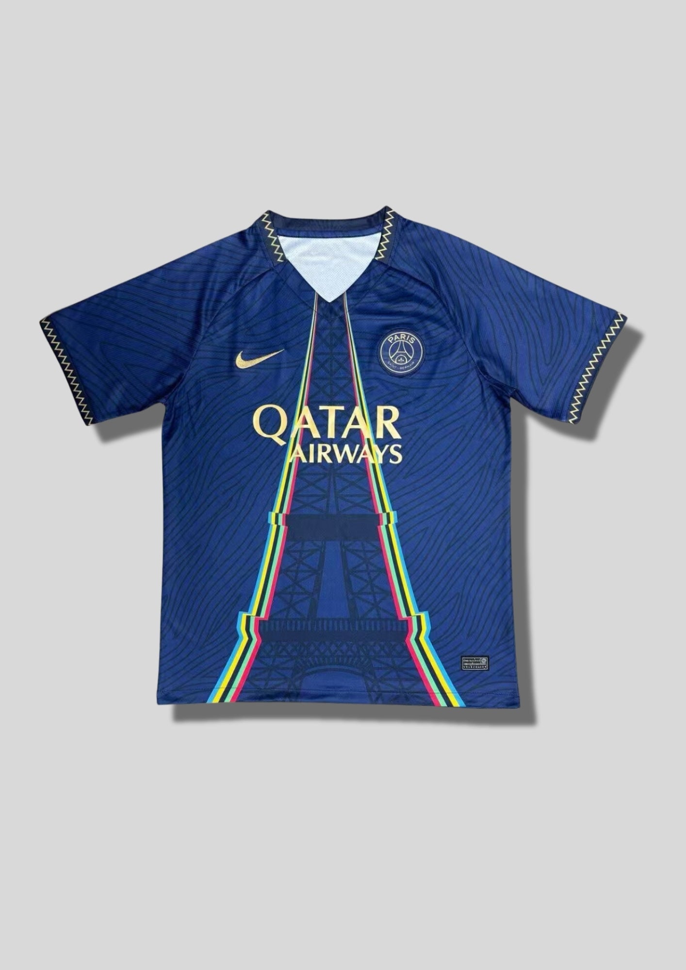 Paris Saint-Germain marine Tour Eiffel : maillot bleu avec un motif de Tour Eiffel stylisée aux contours multicolores (jaune, rose, bleu), logos dorés et col en V à motifs zigzag. GoalKits