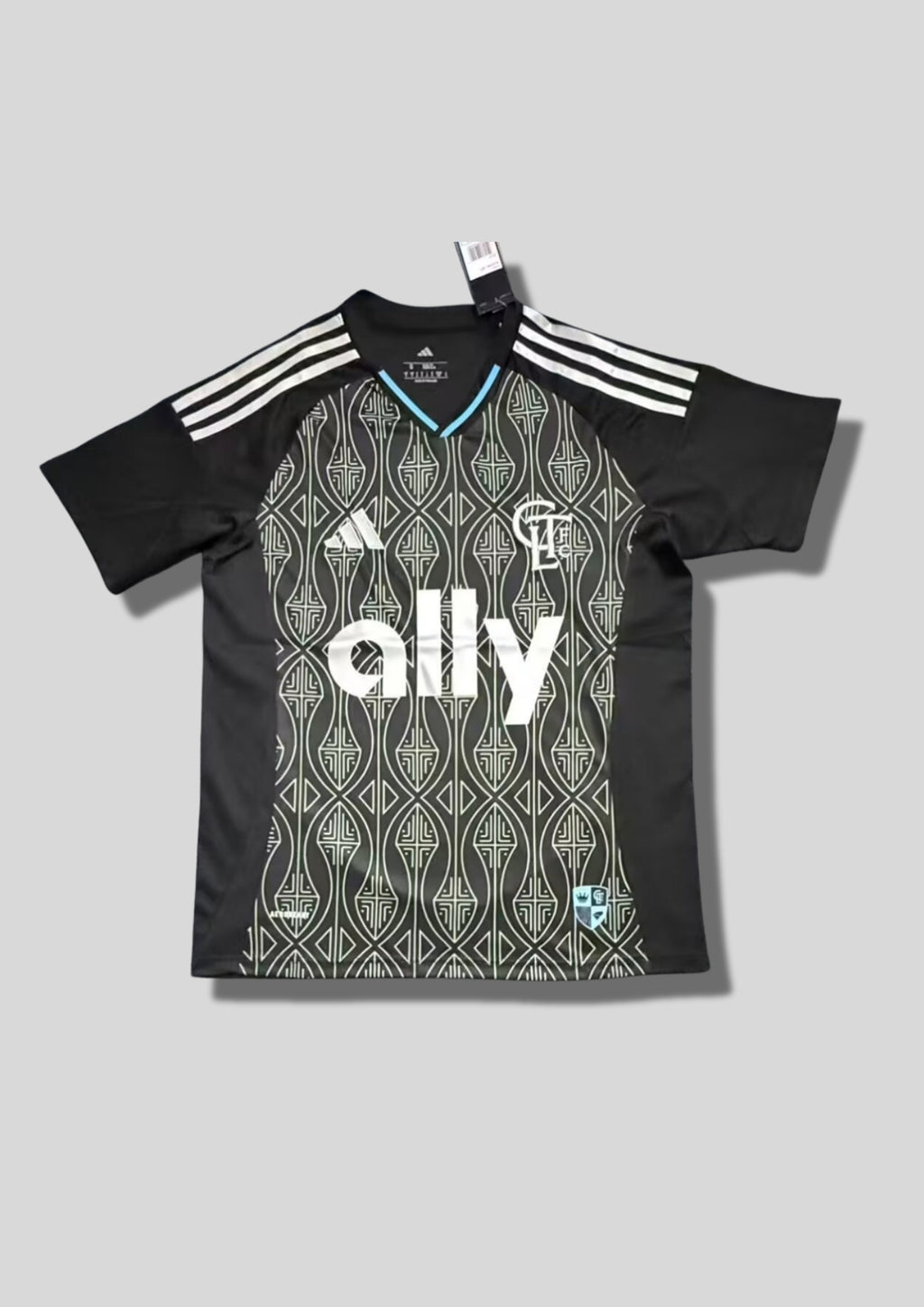 Charlotte FC Home 24/25 : Noir avec manches et panneaux latéraux unis et torse orné de motifs géométriques gris clair et sponsor "ally". GoalKits