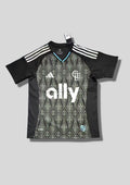 Charlotte FC Home 24/25 : Noir avec manches et panneaux latéraux unis et torse orné de motifs géométriques gris clair et sponsor "ally". GoalKits