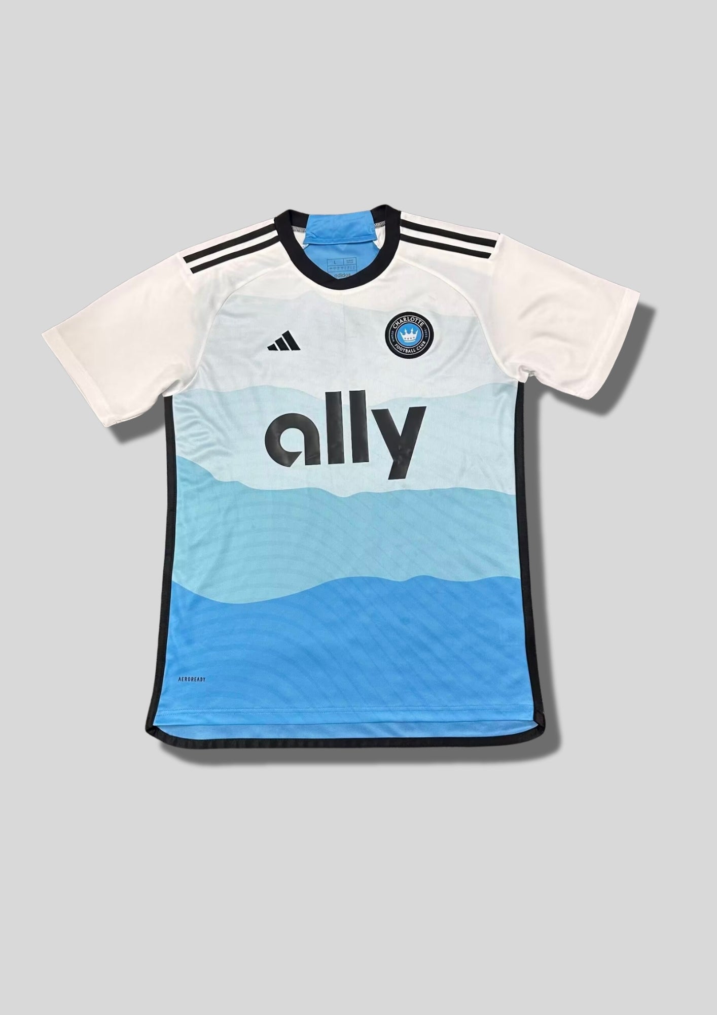 Charlotte FC Away 24/25 : Blanc avec un dégradé de vagues bleues sur le torse et sponsor "ally" GoalKits