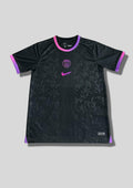 Paris Saint-Germain noir motif baroque : maillot noir orné d'un motif de volutes baroque texturé, avec logos centré et col/manches aux accents dégradés de rose et de violet. GoalKits