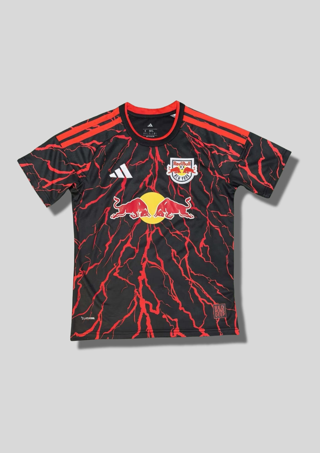 New York Red Bulls Pre-Match 24/25 : Noir avec des motifs d'éclairs rouges vifs sur tout le maillot et le logo Red Bull central. GoalKits