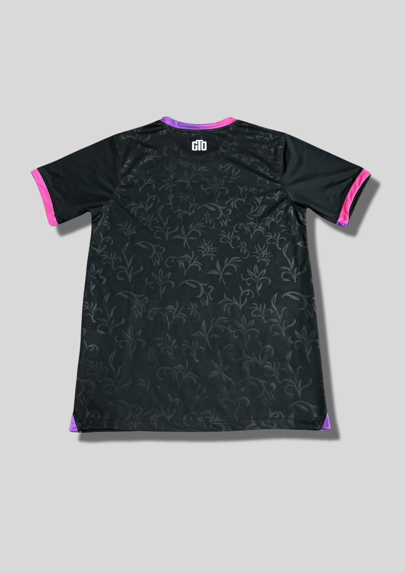 Paris Saint-Germain noir motif baroque : maillot noir orné d'un motif de volutes baroque texturé, avec logos centré et col/manches aux accents dégradés de rose et de violet. GoalKits
