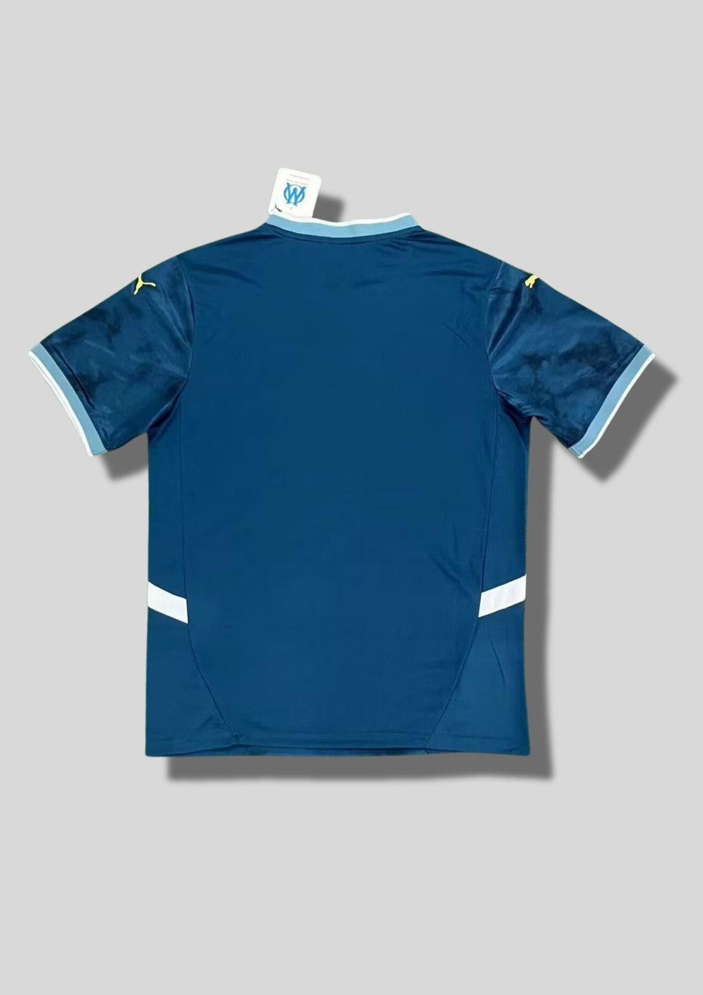Olympique de Marseille extérieur 2024-2025 : maillot bleu turquoise avec un motif effet "tie-dye" ou fumée sombre, logos et sponsor CMA CGM jaunes, détails blancs sur les flancs. GoalKits