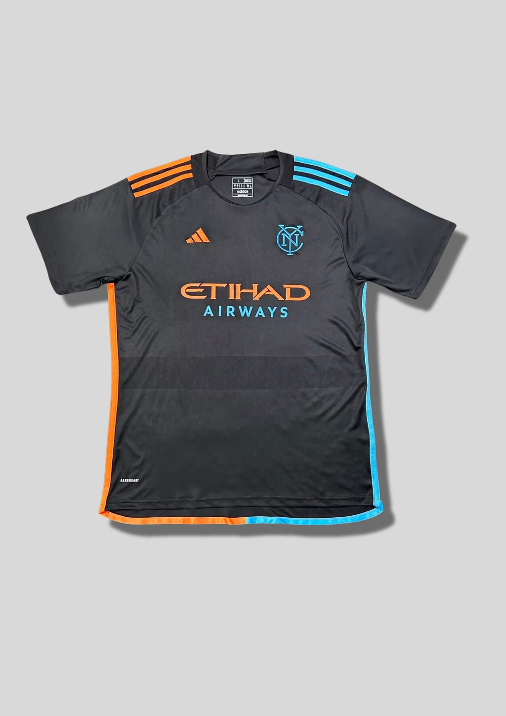 New York City FC (NYCFC) Away 24/25 : Noir avec des détails asymétriques orange (côté droit) et bleu ciel (côté gauche). GoalKits