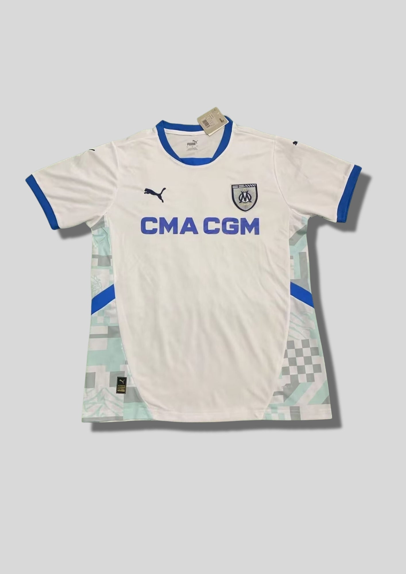 Olympique de Marseille domicile 2024-2025 : maillot blanc avec un col rond et des bords de manches bleu roi, panneaux latéraux décorés de motifs géométriques gris et menthe, blason classique et sponsor CMA CGM bleu. GoalKits