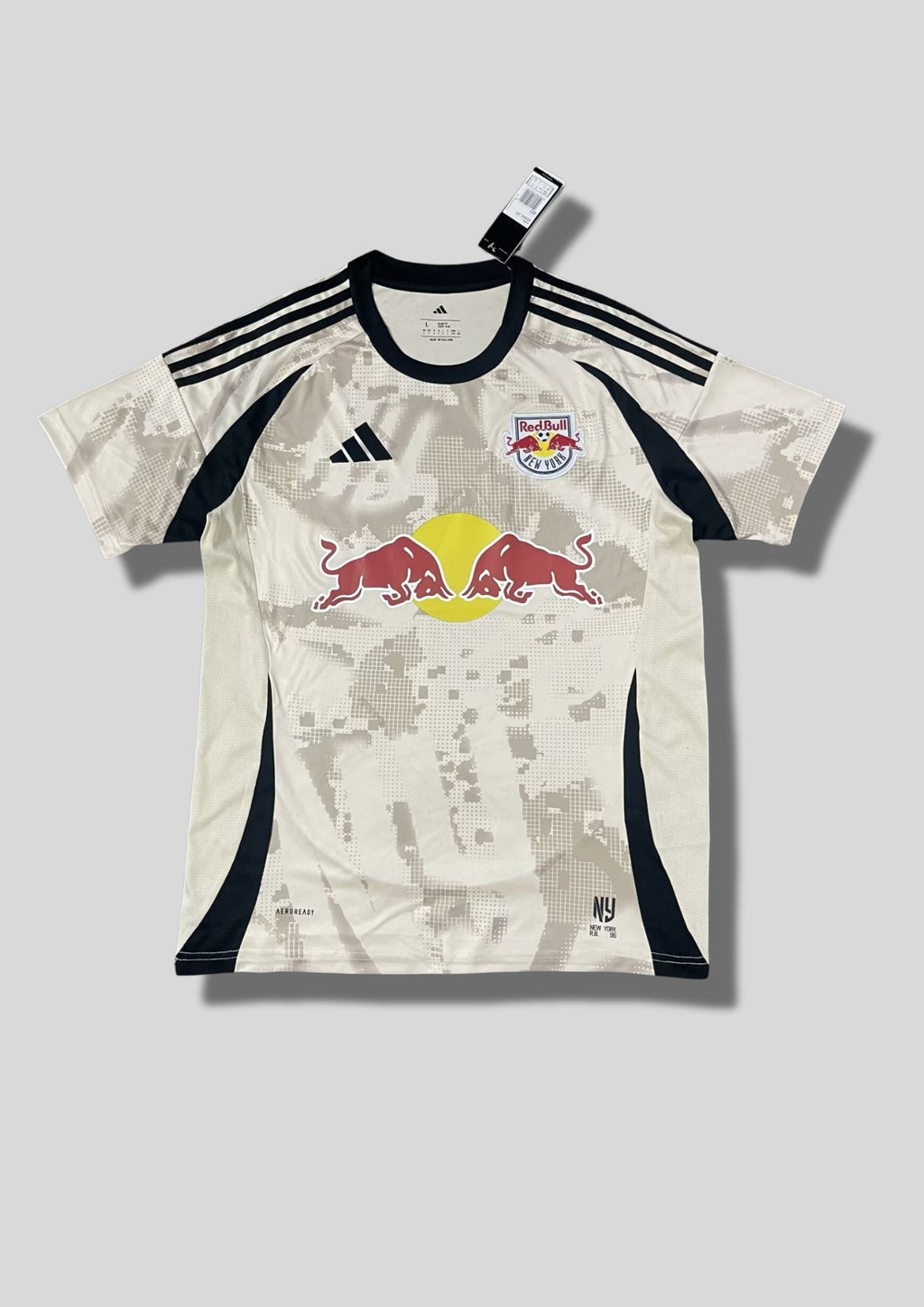 New York Red Bulls Away 24/25 : Crème avec des motifs graphiques grisés en pixels et détails noirs sur les flancs et les épaules. GoalKits