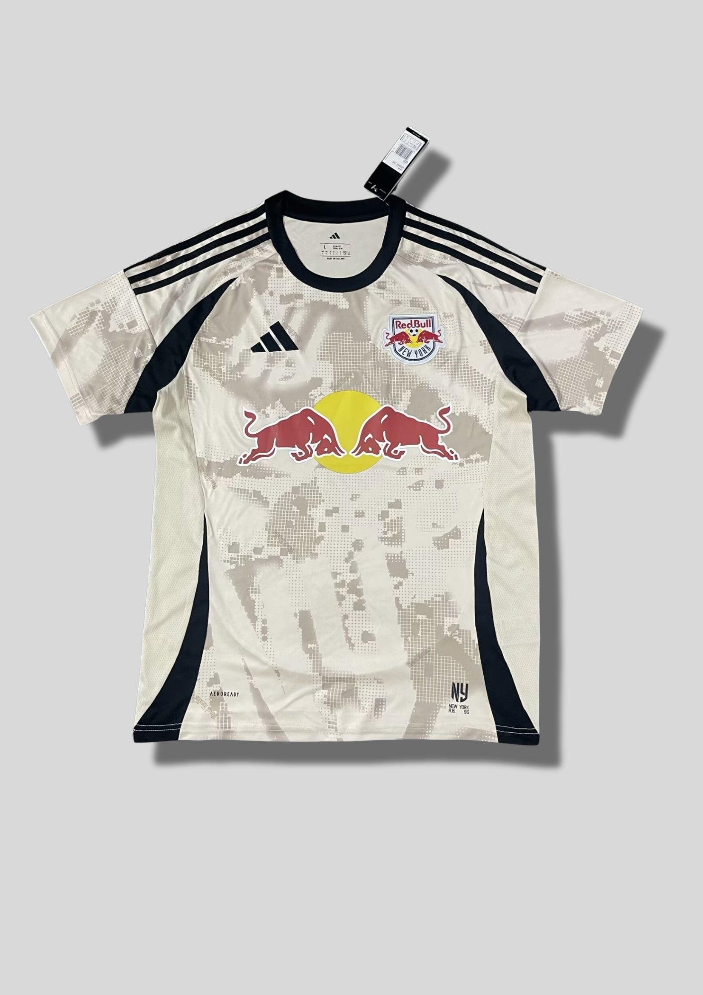 New York Red Bulls Away 24/25 : Crème avec des motifs graphiques grisés en pixels et détails noirs sur les flancs et les épaules. GoalKits