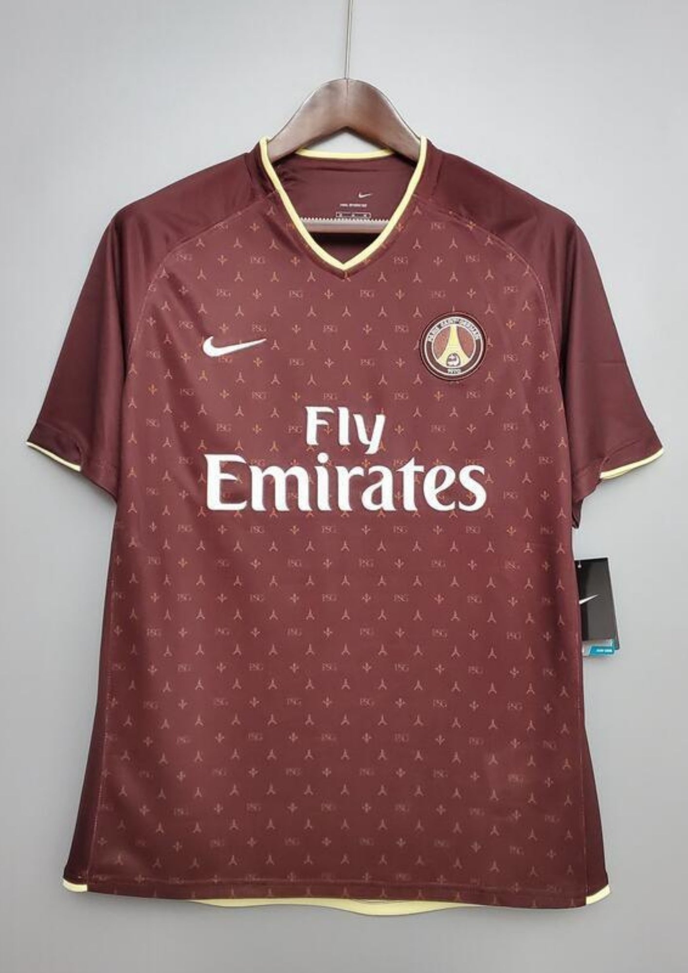 Paris Saint-Germain bordeaux monogramme : maillot couleur prune/bordeaux avec un motif monogramme "PSG" et Tour Eiffel sur tout le torse, col en V et liserés jaune pâle, sponsor Fly Emirates. GoalKits