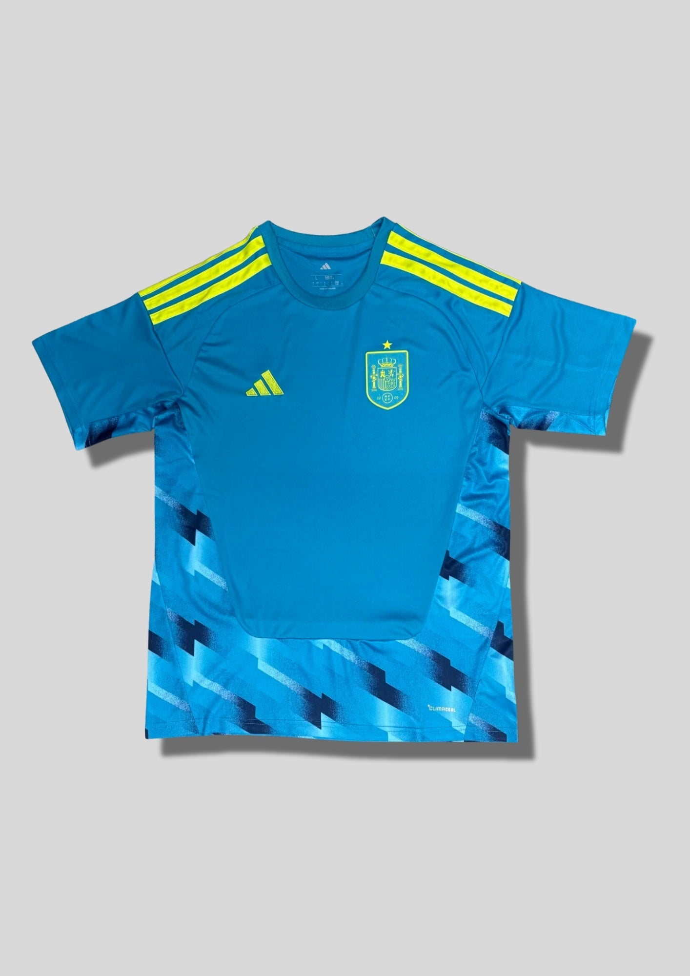 Espagne Training/Pre-Match 2024 : Bleu turquoise, motifs géométriques en dégradé sur le bas et bandes jaune fluo. GoalKits