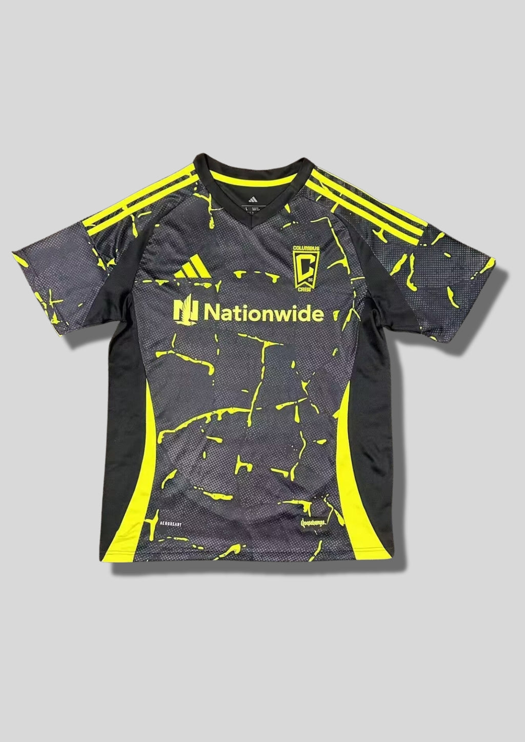 Columbus Crew Pre-Match 24/25 : Noir avec des motifs graphiques "éclaboussures" jaune fluo sur l'ensemble et sponsor "Nationwide". GoalKits