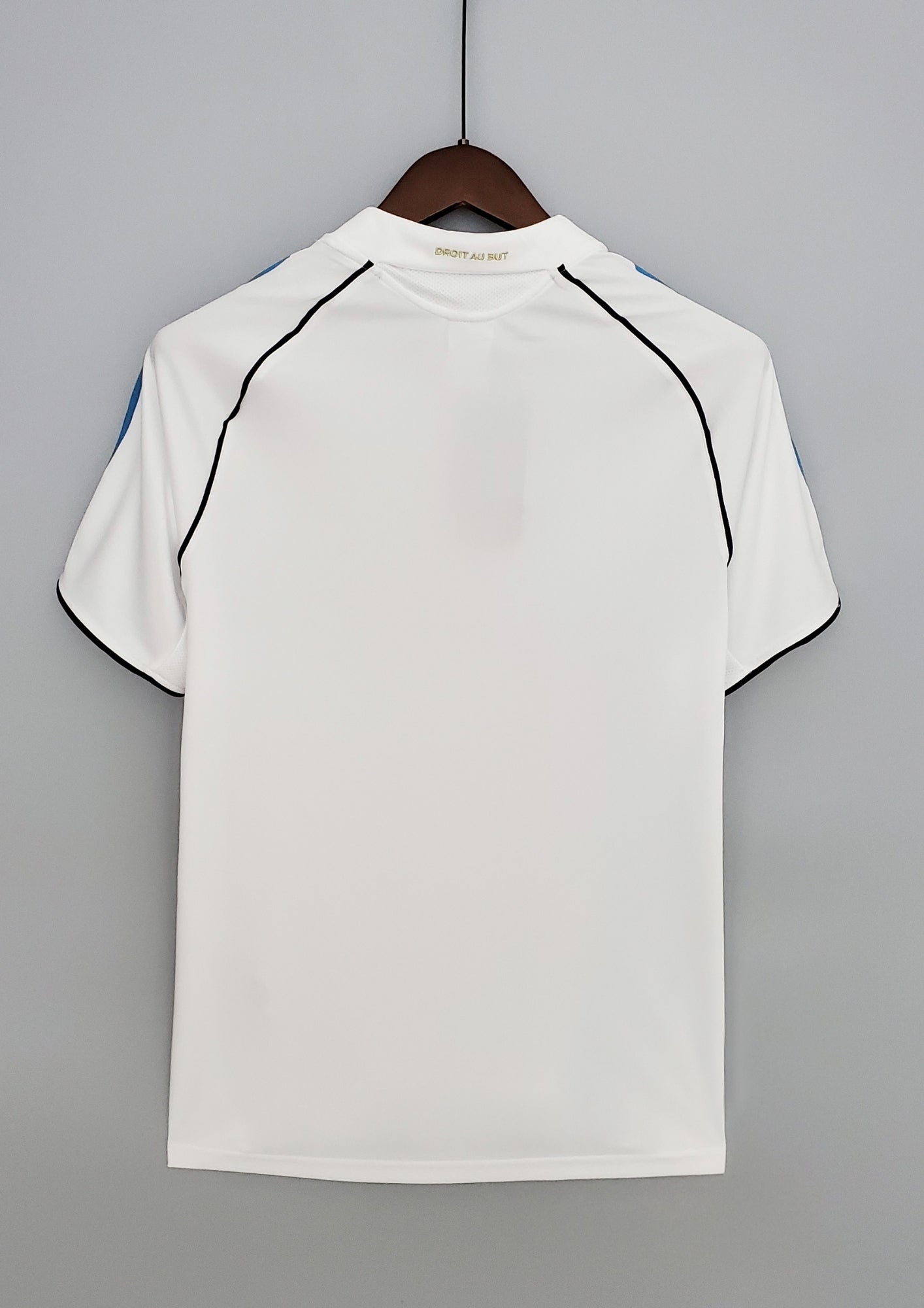 OM domicile 2006-2007 : maillot blanc Adidas avec une large croix bleu ciel asymétrique sur le torse, des liserés noirs incurvés et le sponsor Neuf Telecom. GoalKits