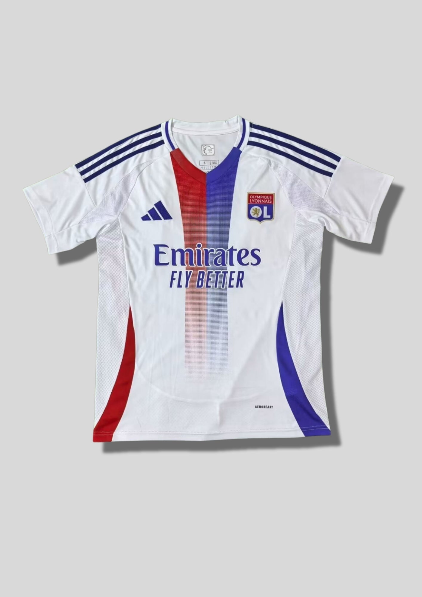 Olympique Lyonnais domicile 2024-2025 : maillot blanc avec deux bandes verticales centrales dégradées rouge et bleue, bandes Adidas bleu marine sur les épaules et sponsor Emirates. GoalKits