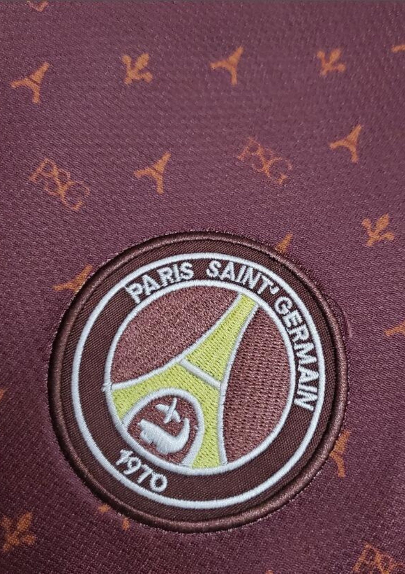 Paris Saint-Germain bordeaux monogramme : maillot couleur prune/bordeaux avec un motif monogramme "PSG" et Tour Eiffel sur tout le torse, col en V et liserés jaune pâle, sponsor Fly Emirates. GoalKits