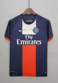 Paris Saint-Germain domicile 2012-2013 : maillot bleu marine avec un large bloc central bicolore blanc sur le haut et rouge sur le bas, liserés rouges aux manches et sponsor Fly Emirates. GoalKits