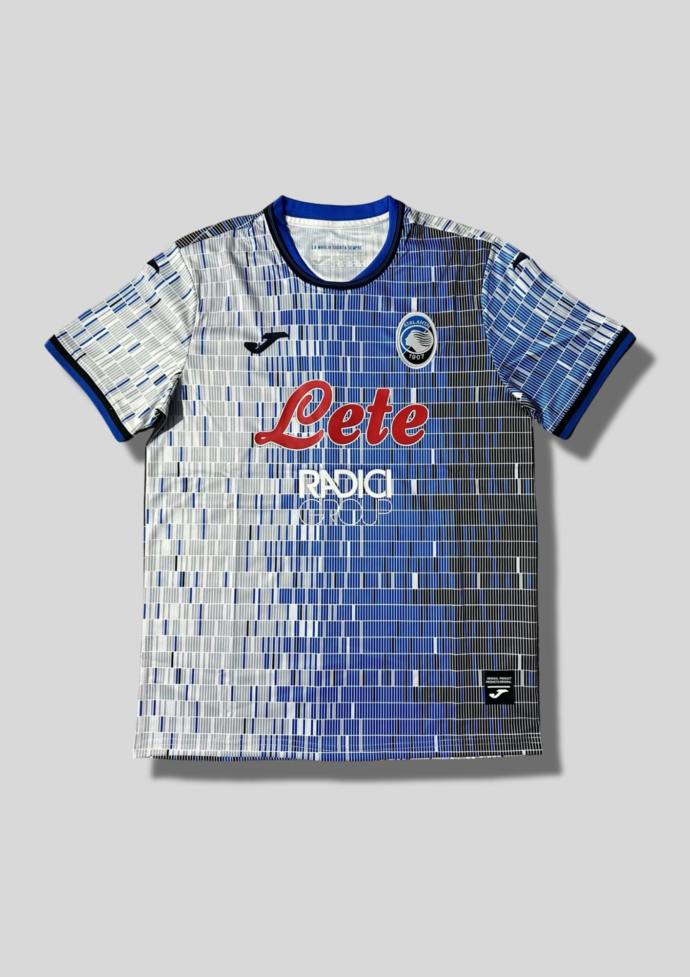 Atalanta Bergame Away 24/25 : Design blanc et bleu avec des motifs en barres verticales pixélisées, logo Joma et sponsors "Lete" et "Radici Group". GoalKits