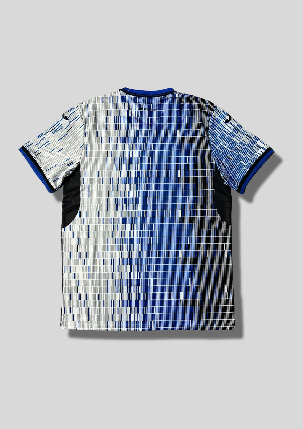 Atalanta Bergame Away 24/25 : Design blanc et bleu avec des motifs en barres verticales pixélisées, logo Joma et sponsors "Lete" et "Radici Group". GoalKits
