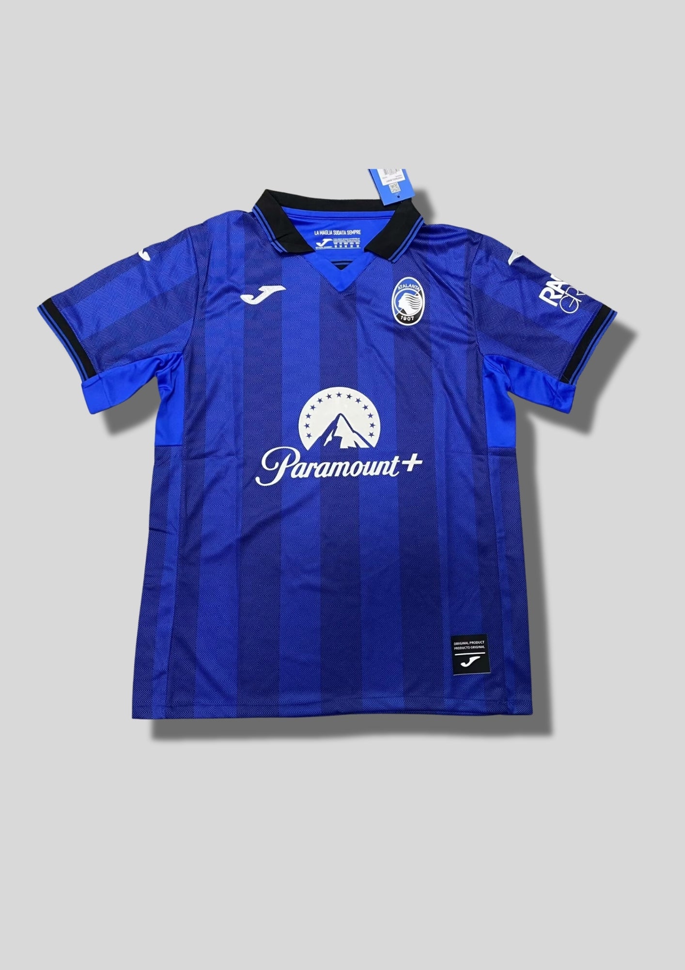Atalanta Bergame Away 24/25 : Design blanc et bleu avec des motifs en barres verticales pixélisées, logo Joma et sponsors "Lete" et "Radici Group". GoalKits