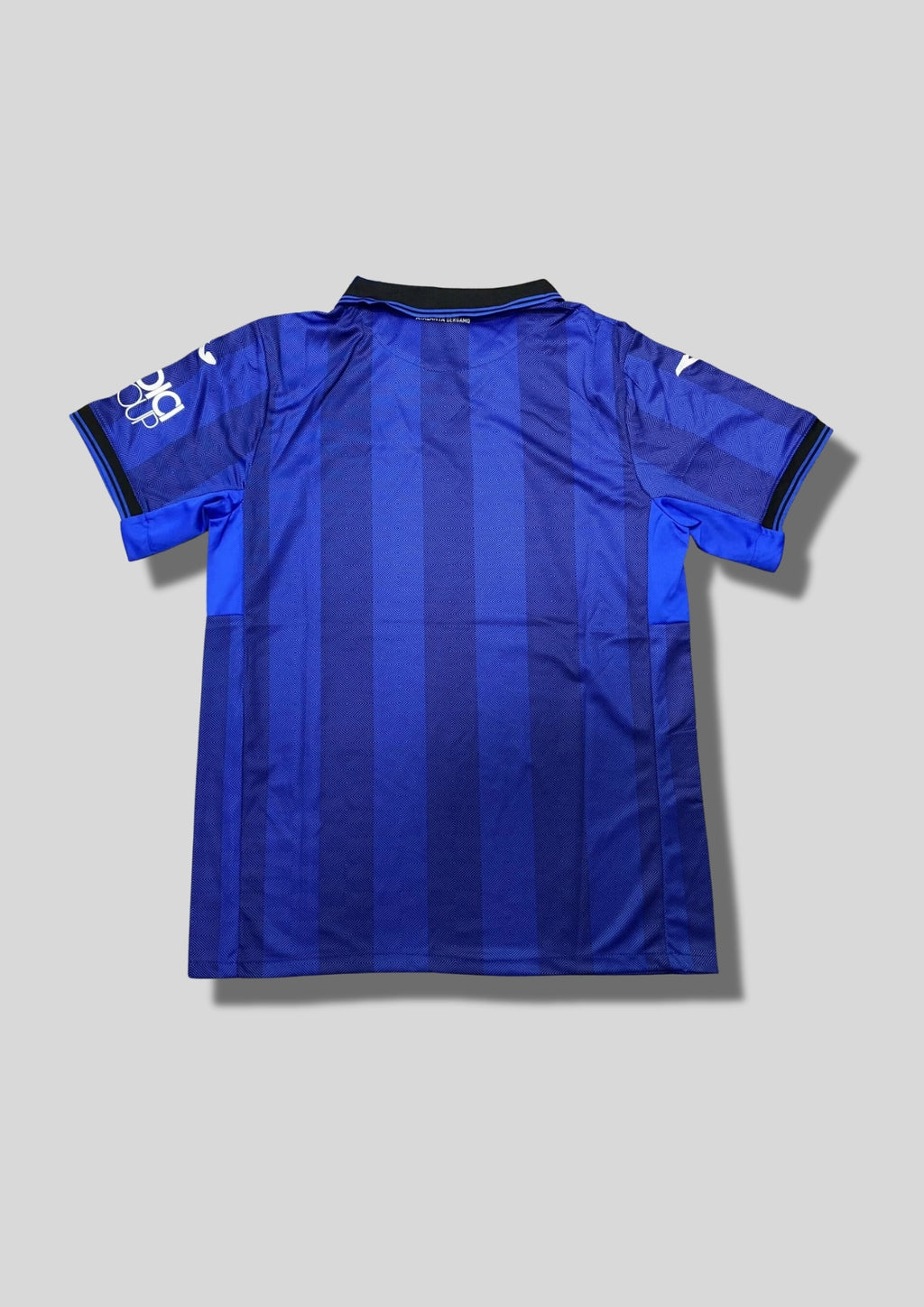 Atalanta Bergame Away 24/25 : Design blanc et bleu avec des motifs en barres verticales pixélisées, logo Joma et sponsors "Lete" et "Radici Group". GoalKits