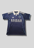 Paris FC domicile 2024-2025 : maillot bleu marine Adidas avec de fines rayures verticales, un col polo blanc contrastant et le sponsor Bahrain Victorious. GoalKits