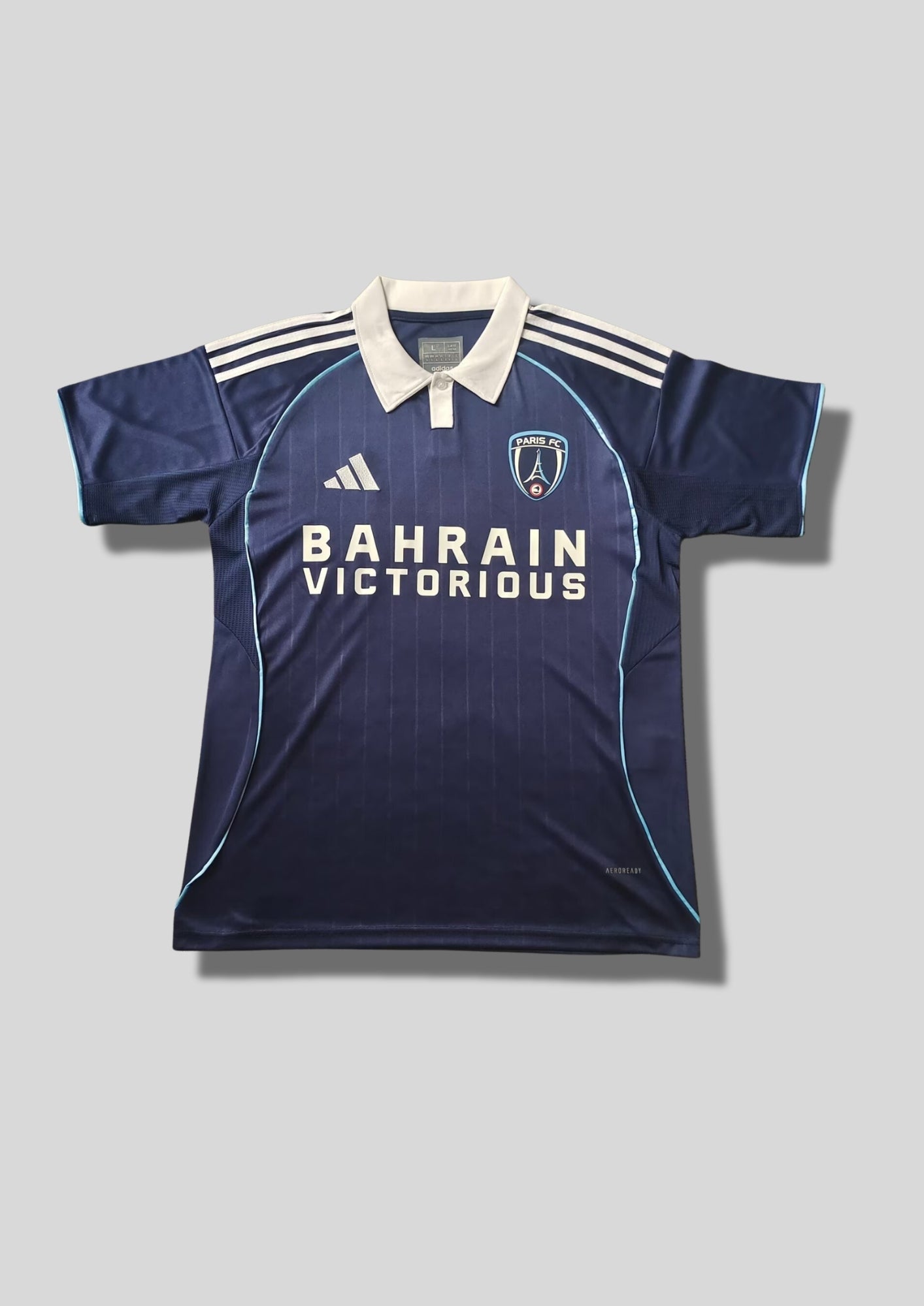 Paris FC domicile 2024-2025 : maillot bleu marine Adidas avec de fines rayures verticales, un col polo blanc contrastant et le sponsor Bahrain Victorious. GoalKits