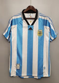 rgentine 1998 (Domicile) Rayures ciel et blanc, col noir en V, logo Adidas central, blason AFA avec lauriers dorés. GoalKits