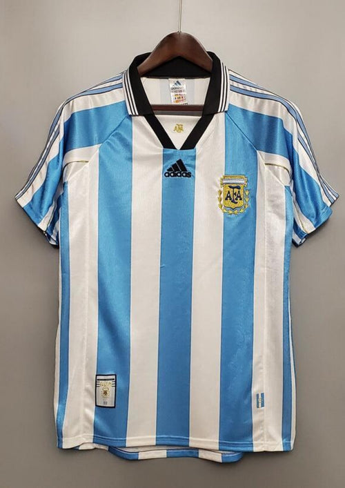 rgentine 1998 (Domicile) Rayures ciel et blanc, col noir en V, logo Adidas central, blason AFA avec lauriers dorés. GoalKits