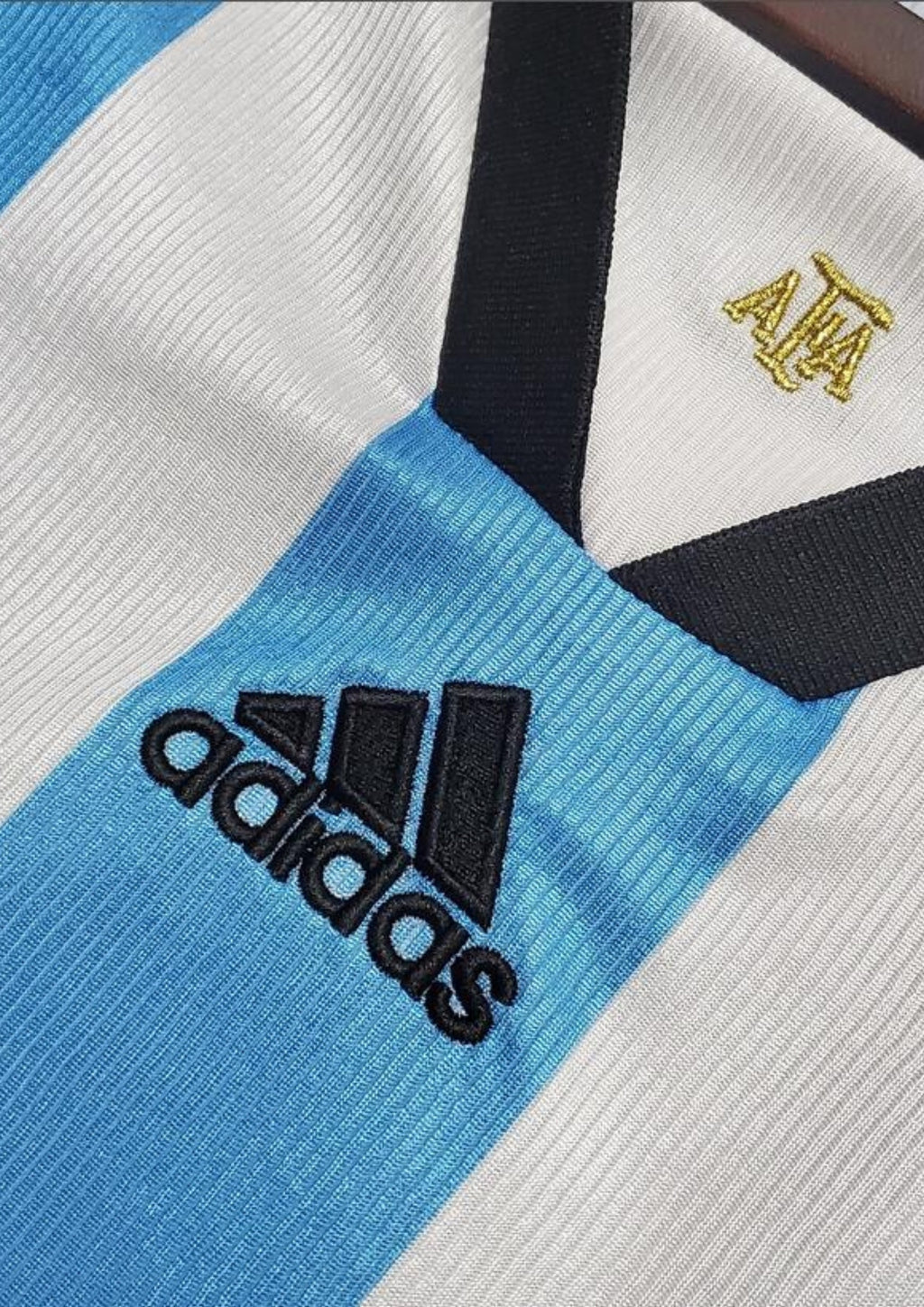 rgentine 1998 (Domicile) Rayures ciel et blanc, col noir en V, logo Adidas central, blason AFA avec lauriers dorés. GoalKits