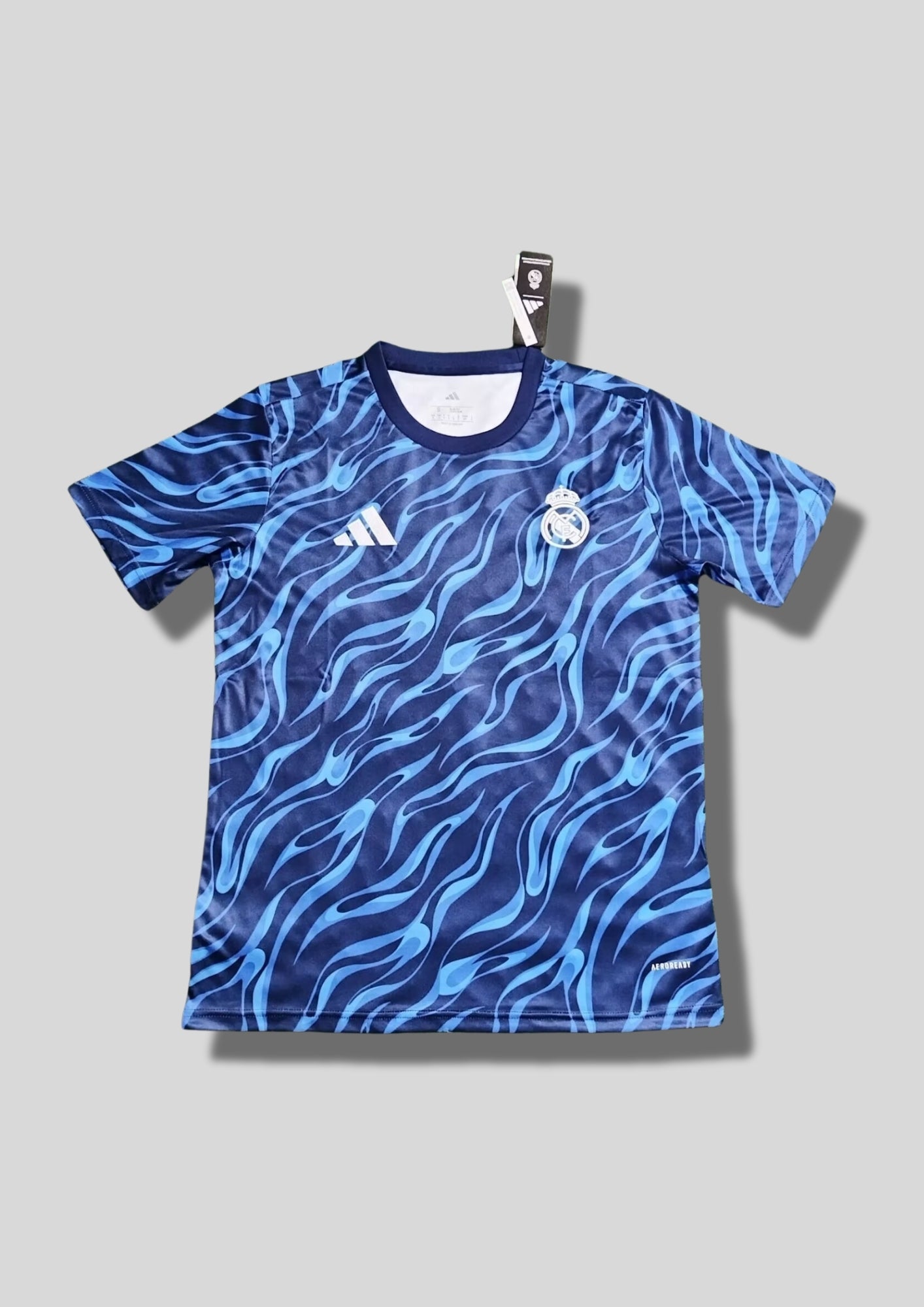 Real Madrid : Maillot d'entraînement / Édition Spéciale – Motif intégral de flammes bleues (style vagues/eau) sur fond bleu marine, sans sponsor central. GoalKits