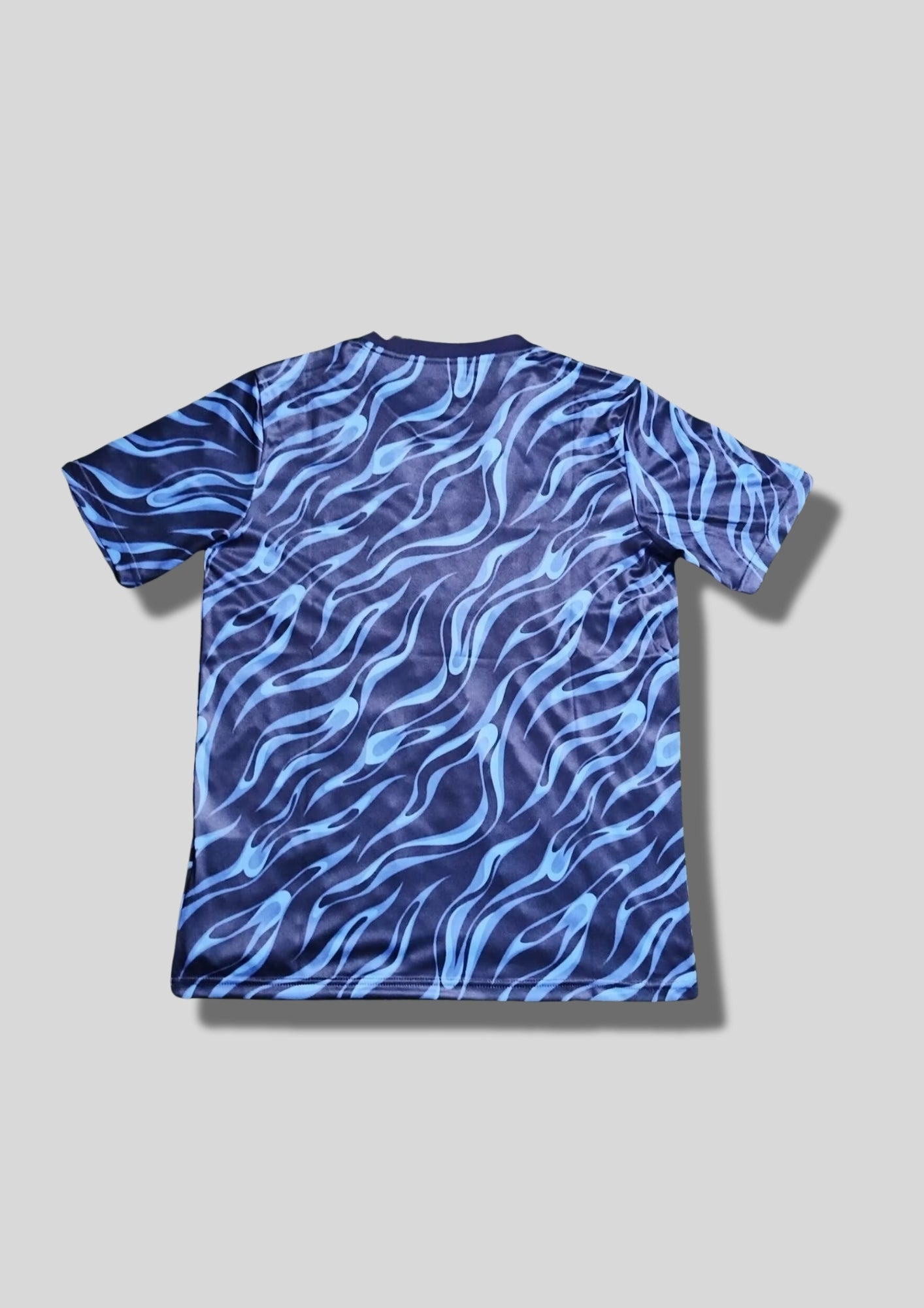 Real Madrid : Maillot d'entraînement / Édition Spéciale – Motif intégral de flammes bleues (style vagues/eau) sur fond bleu marine, sans sponsor central. GoalKits