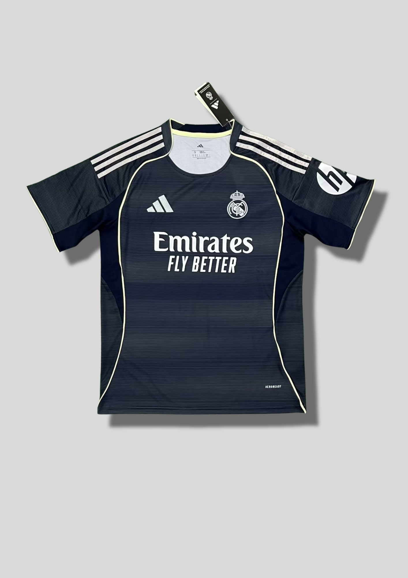 Real Madrid : Maillot d'entraînement / Édition Spéciale – Gris anthracite avec de fines rayures horizontales, détails jaune fluo (volt) et logo HP sur la manche. GoalKits