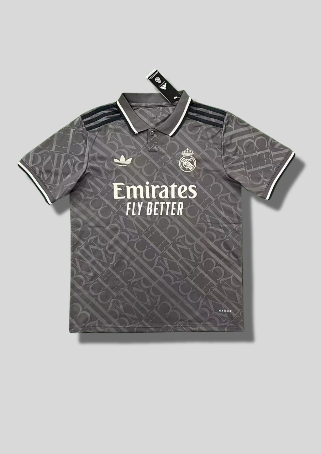 Real Madrid : Maillot d'entraînement / Édition Spéciale – Gris anthracite avec un motif monogramme intégral de lettres entrelacées, col polo boutonné et logos blancs. GoalKits