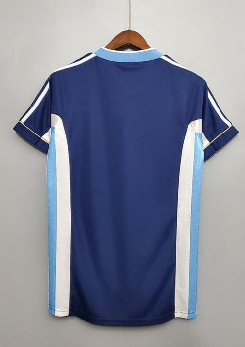 Argentine 1998 (Extérieur) Bleu marine, col en V ciel et blanc, bandes latérales tricolores, logo Adidas central blanc. GoalKits