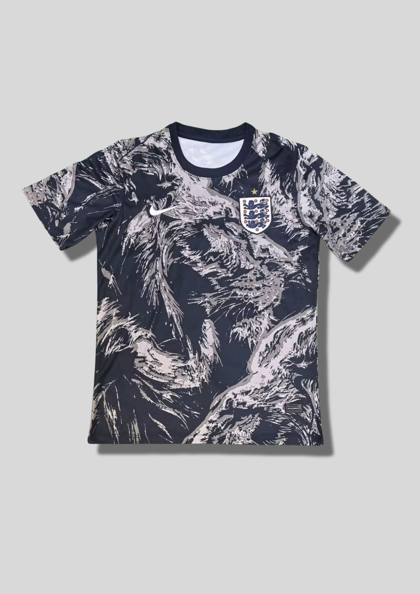 Angleterre 2024 (Pre-Match) Noir et gris anthracite, motifs graphiques abstraits "pelage de lion" sur l'ensemble, virgule Nike blanche et écusson des Three Lions classique. GoalKits