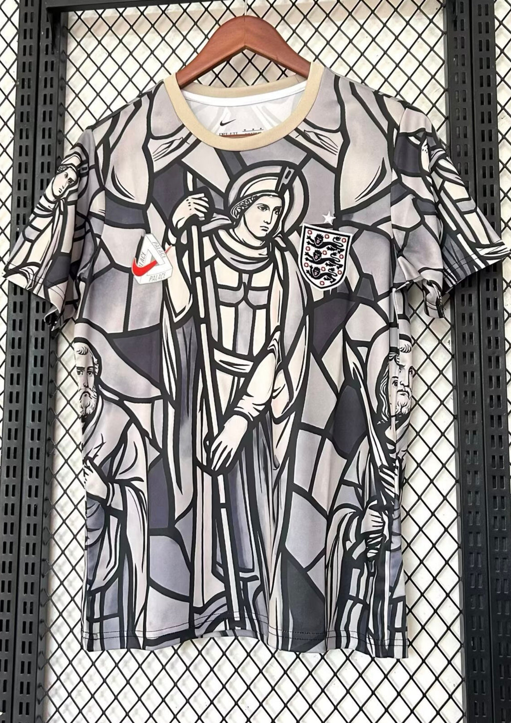 Angleterre 2024 (Concept x Palace) Gris et beige, motif intégral style vitrail médiéval représentant des figures religieuses, logo Nike surmonté du triangle Palace. GoalKits