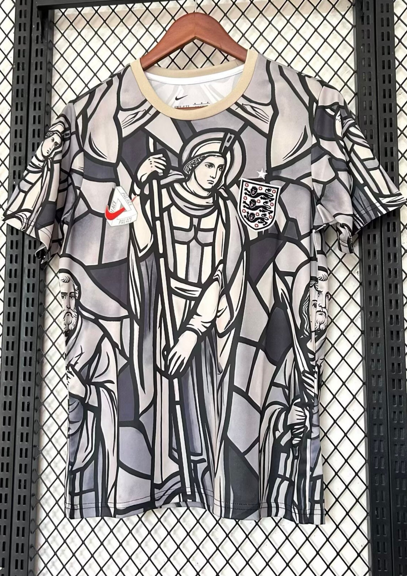 Angleterre 2024 (Concept x Palace) Gris et beige, motif intégral style vitrail médiéval représentant des figures religieuses, logo Nike surmonté du triangle Palace. GoalKits