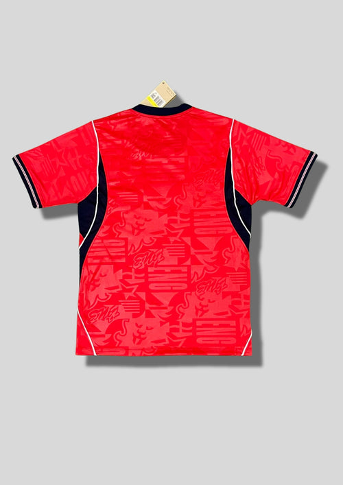 Angleterre 2024 (Pre-Match / Training) Rouge vif avec motifs graphiques "ENG" et lions en ton sur ton, col et détails latéraux bleu marine, logos centrés. GoalKits
