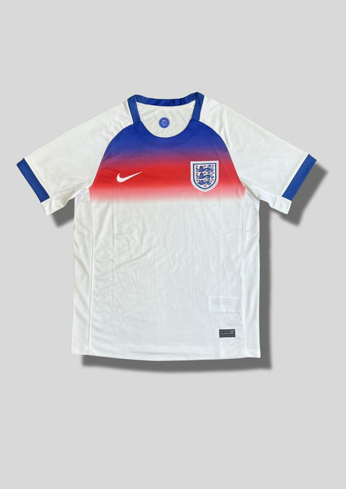 Angleterre 2024 (Training / Pre-Match) Blanc avec un dégradé horizontal bleu et rouge sur le haut du torse, col et bordures de manches bleus, virgule Nike blanche. GoalKits
