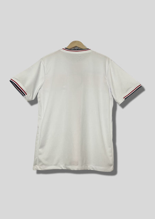 Angleterre 2024 (Concept/Cross) Blanc avec une large croix de Saint-Georges rouge centrée, bordée de fines lignes bleu marine. Le logo Nike et l'écusson des Three Lions sont placés de part et d'autre de la croix. GoalKits