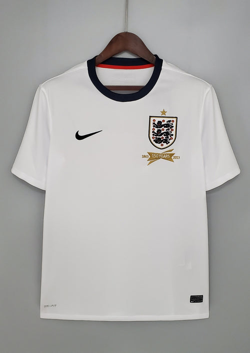 Angleterre 2024 (Concept/Cross) Blanc avec une large croix de Saint-Georges rouge centrée, bordée de fines lignes bleu marine. Le logo Nike et l'écusson des Three Lions sont placés de part et d'autre de la croix. GoalKits