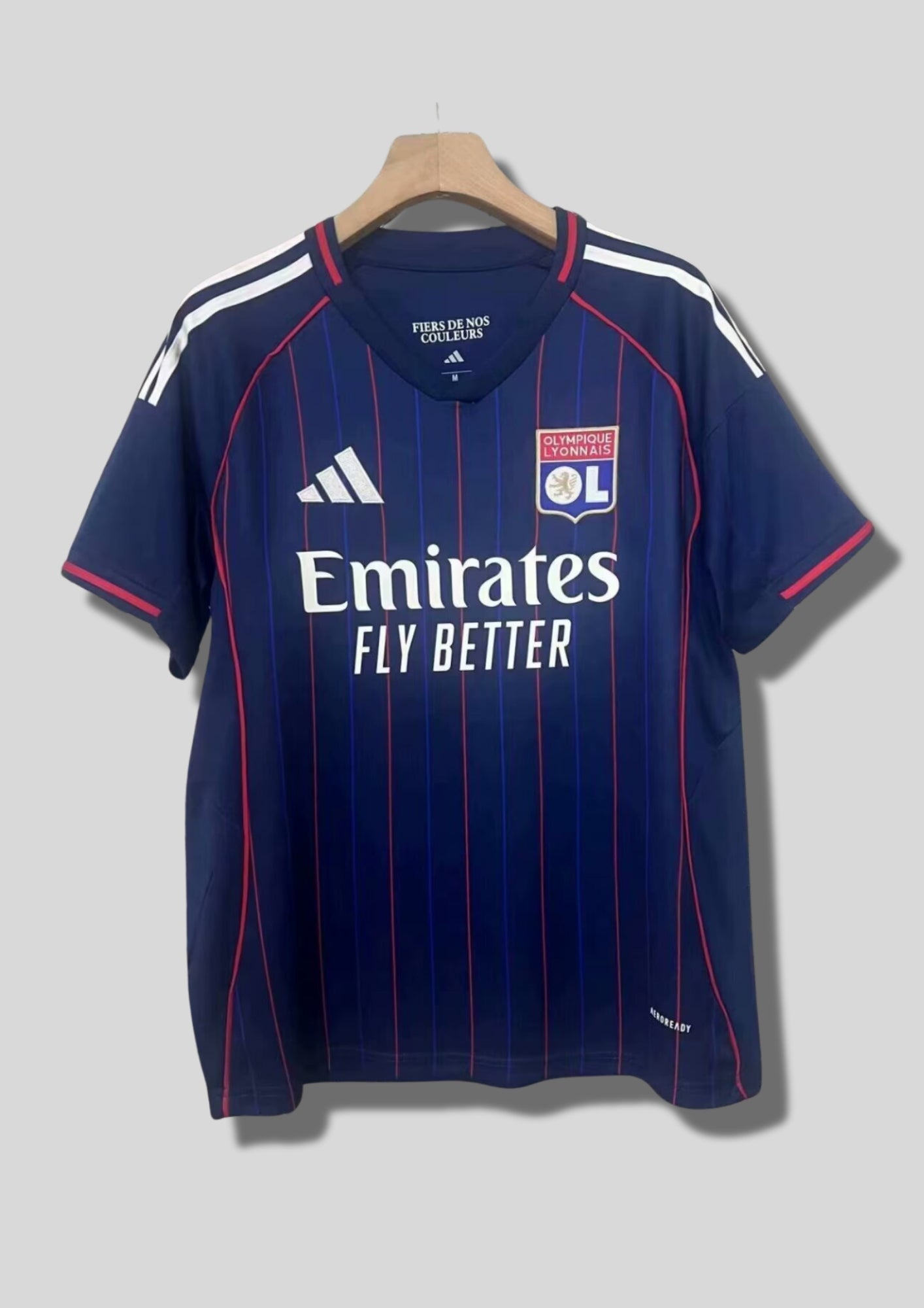 Olympique Lyonnais extérieur 2023-2024 : maillot bleu marine avec de fines rayures verticales rouges et bleues, col et manches avec liserés rouges et blancs, logos blancs. GoalKits