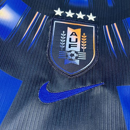Uruguay (Édition Coupe du Monde) Bleu marine avec un motif circulaire de rayons bleus et blancs sur le torse, virgule Nike bleue et écusson de l'Uruguay centré sous quatre étoiles. GoalKits