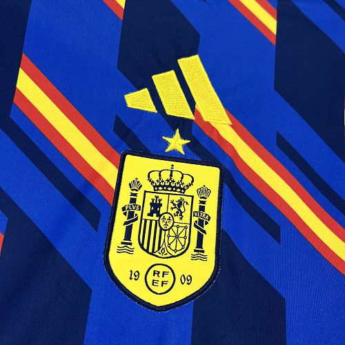 Espagne (Édition Coupe du Monde) Bleu royal, motifs géométriques en diagonale aux couleurs du drapeau (rouge et jaune), logo Adidas et écusson espagnol jaunes centrés. GoalKits